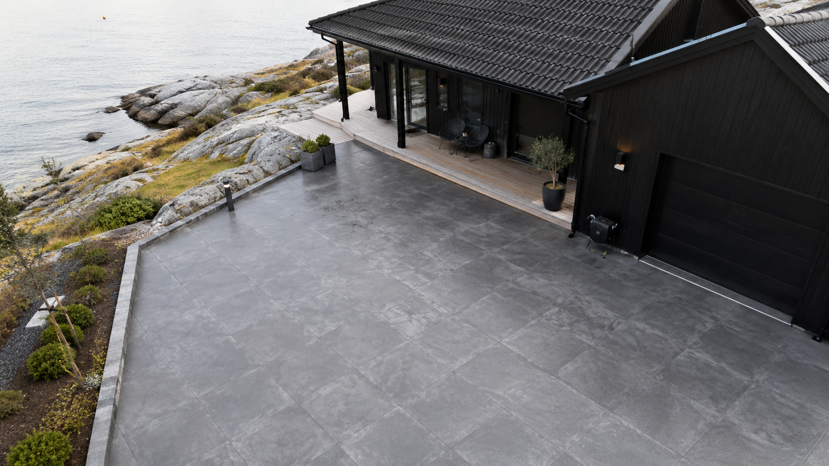 Skurad och glättad betongyta med sågade fogar i rutmönster på stor uteplats framför mörk villa vid havet
